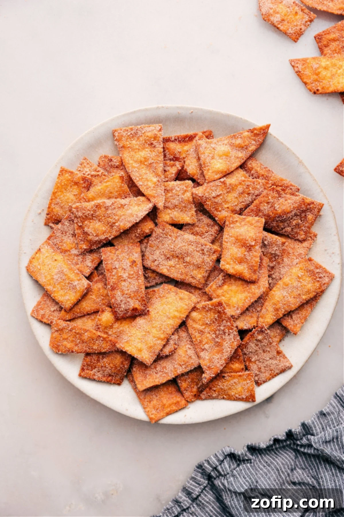 Crispy Cinnamon Sugar Chips piled high on a white plate, glistening with sugar and spice, ready to be enjoyed.