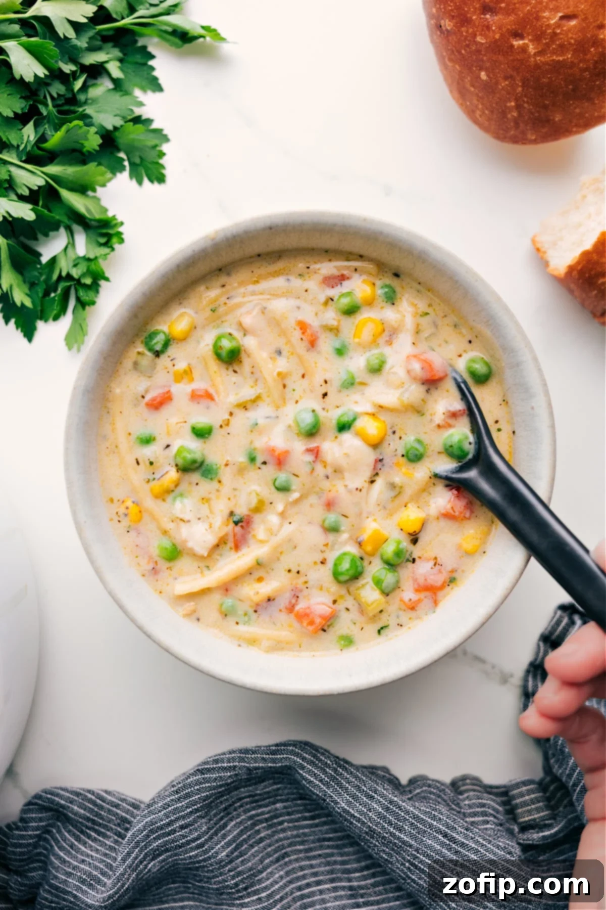 A bowl of rich, creamy chicken noodle soup, garnished with fresh herbs and ready to be enjoyed.