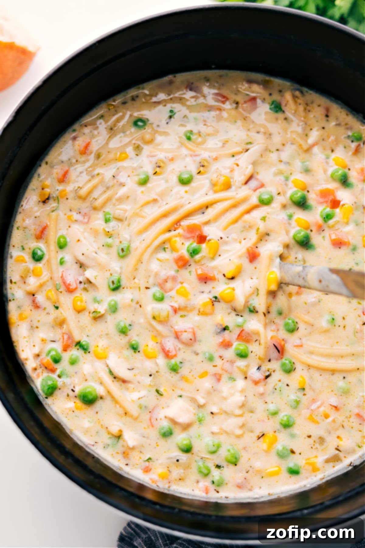 A large pot filled with steaming, golden creamy chicken noodle soup, ready to be served and enjoyed by the family.