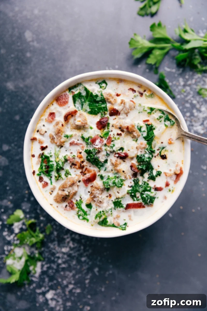 A steaming bowl of Easy Zuppa Toscana soup, richly garnished with crispy bacon, fresh kale, and grated Parmesan cheese, invitingly presented on a rustic wooden surface.