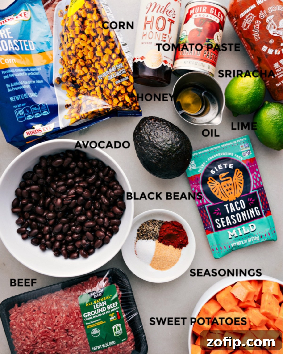 A colorful array of fresh ingredients for the Ground Beef Taco Bowl, including diced sweet potatoes, corn, black beans, ripe avocado, ground beef, and spices, all prepped and ready for cooking.