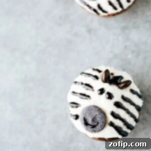 Close-up of a delightful zebra cupcake, featuring black and white stripes, M&M ears, and a cute candy melt face.