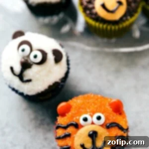 Close-up of a vibrant tiger cupcake, featuring orange sparkling sugar, candy eyes, and black gel stripes.
