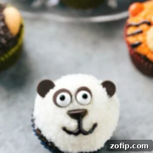 Close-up of a cute panda cupcake, featuring white sparkling sugar, chocolate chip ears and facial features, and candy eyes.