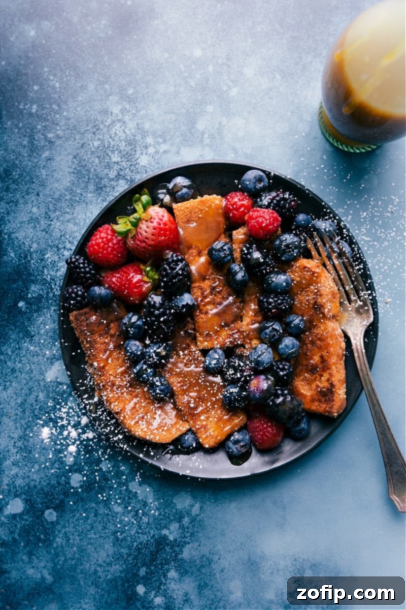 Crispy Cinnamon Toast Crunch French Toast Sticks ready to serve with syrup and fresh berries.