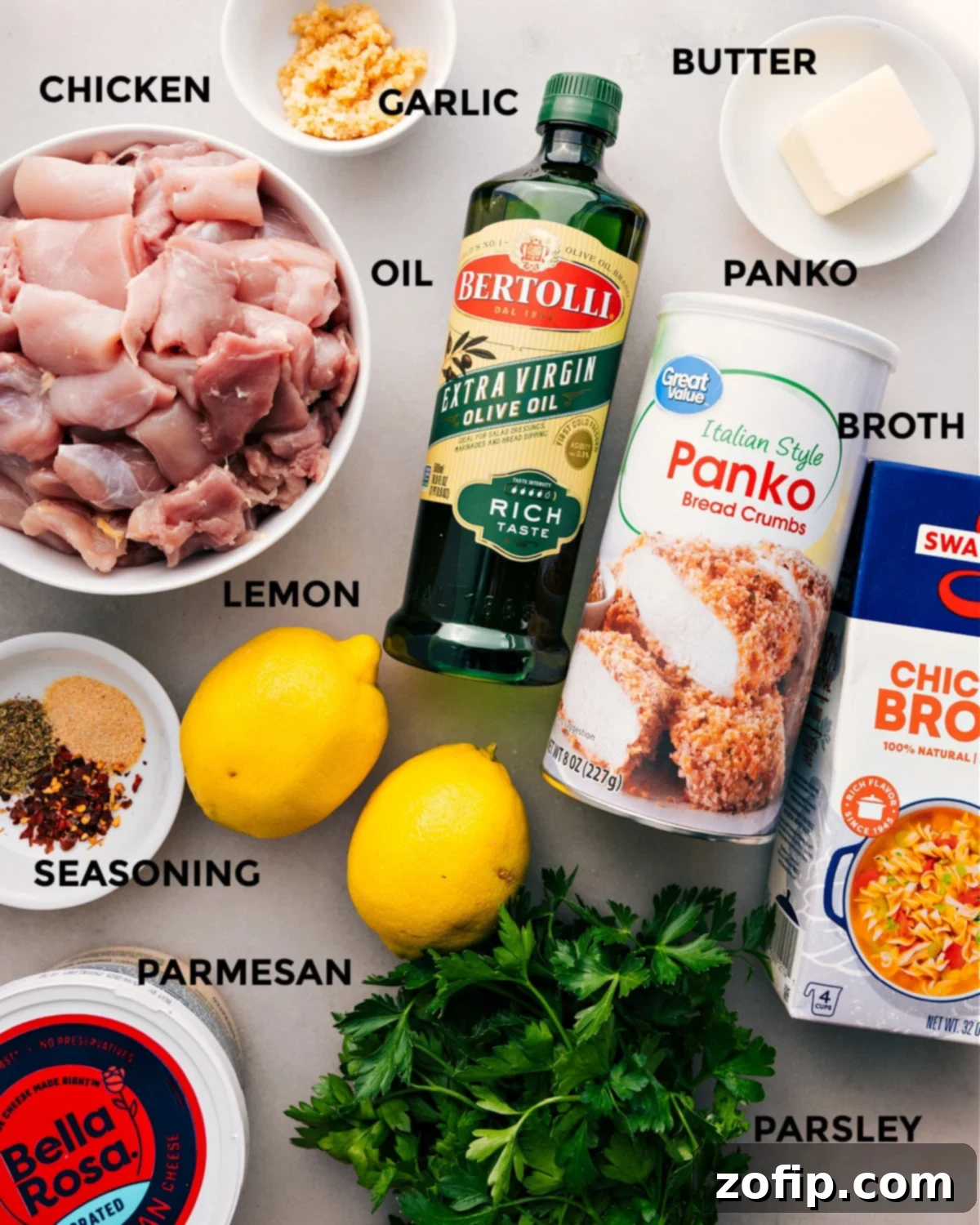 A vibrant display of all Chicken Spiedini ingredients: chicken thighs, olive oil, panko breadcrumbs, butter, fresh garlic, chicken broth, lemons, Italian seasoning, Parmesan cheese, and fresh parsley, all prepped for easy assembly.