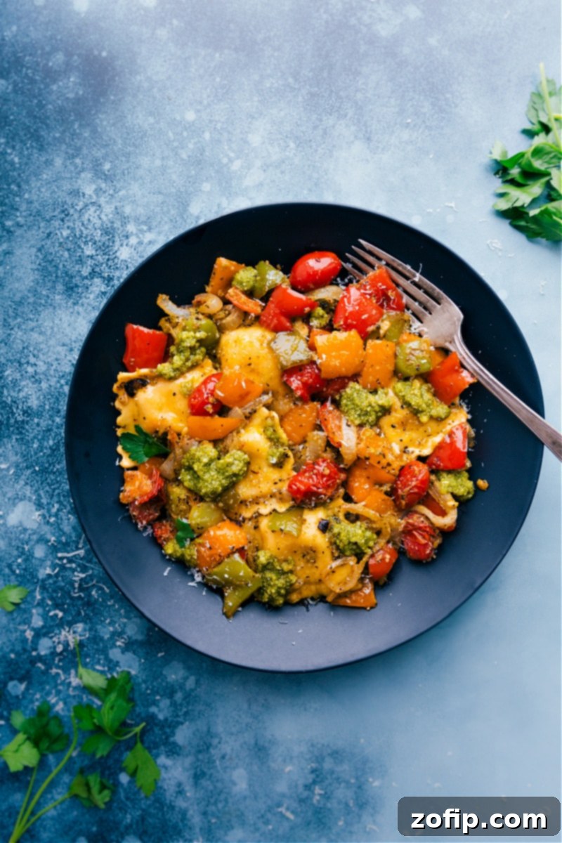 Close-up of a serving of Pesto Ravioli with roasted vegetables, garnished with fresh basil and Parmesan