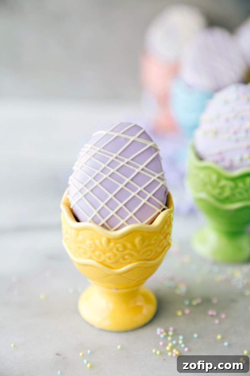 4 Easy Easter Treats 8 Elegant mini egg-shaped petit fours, smoothly frosted and delicately drizzled with white chocolate, perfect for an impressive Easter dessert.