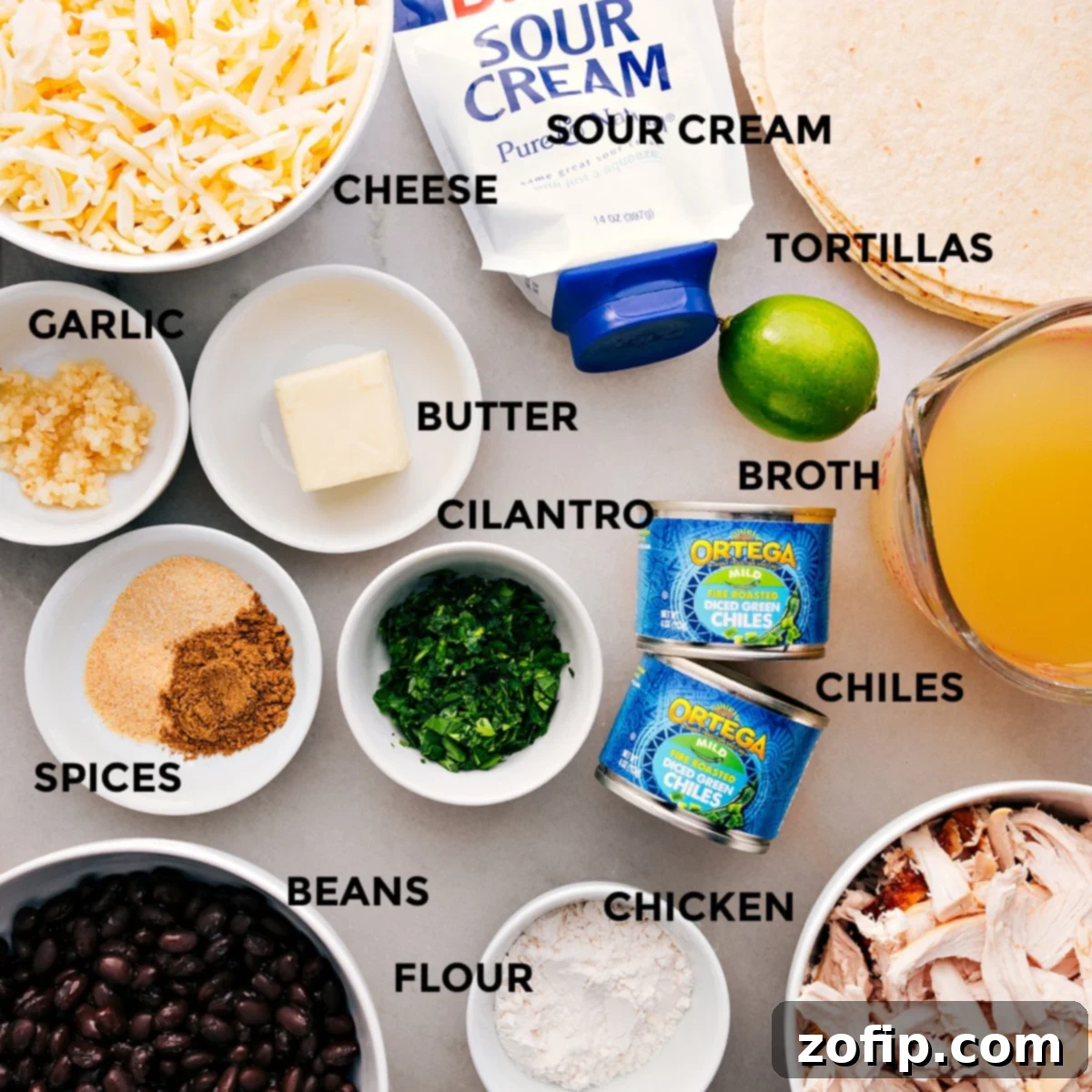 Essential Ingredients for Creamy White Chicken Enchiladas All ingredients laid out for making white chicken enchiladas, including shredded cheese, flour tortillas, sour cream, chicken broth, butter, fresh cilantro, green chiles, minced garlic, various spices, black beans, cooked chicken, and flour.