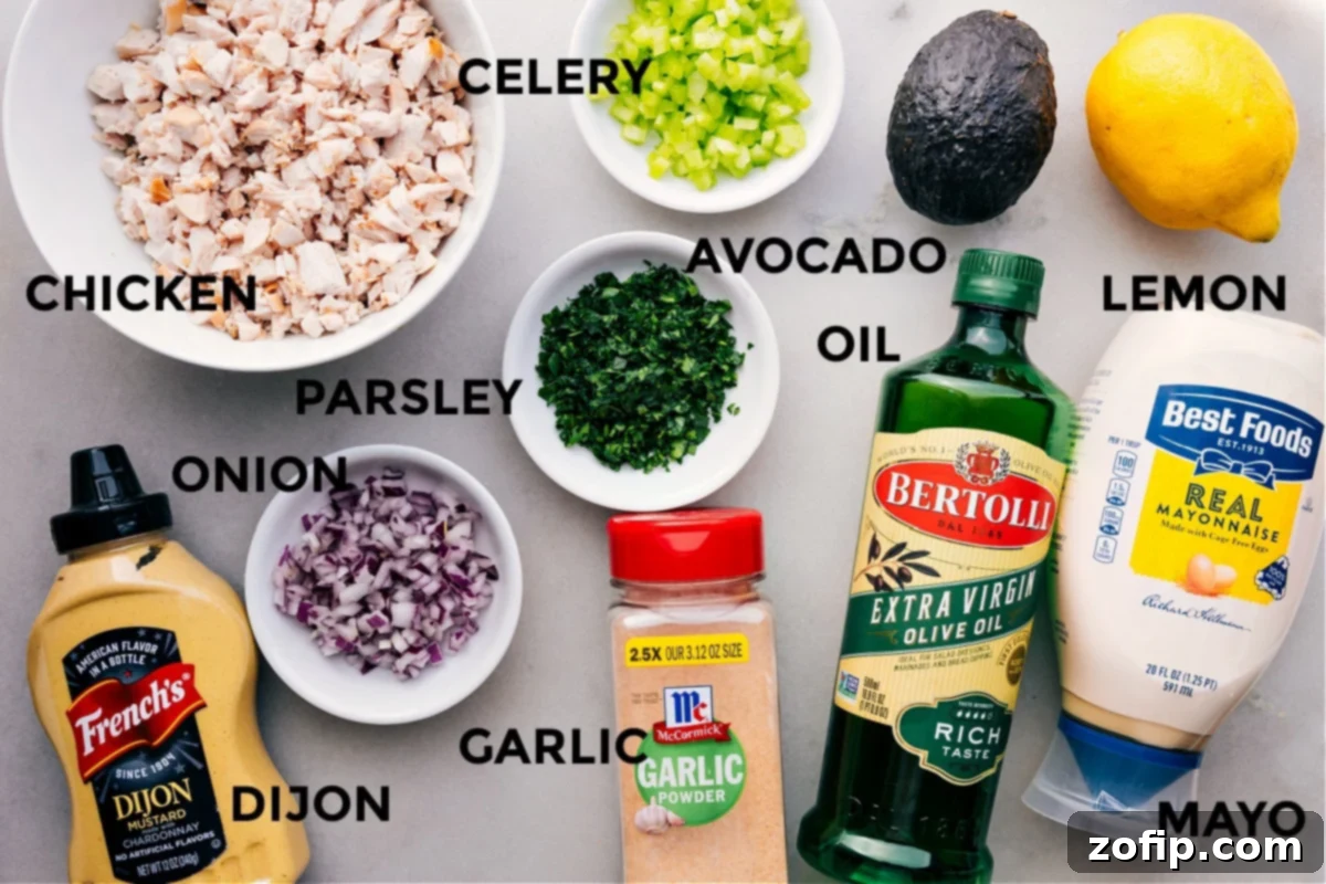 All the fresh ingredients for Chicken Avocado Sandwich, prepped and ready for assembly, including cooked chicken, celery, red onion, parsley, ripe avocado, lemon, mayo, Dijon, garlic powder, olive oil, salt, and pepper.