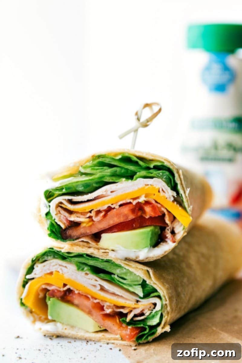 A delicious Turkey Avocado Wrap, perfect for any meal. These family-friendly wraps are quick, easy, and incredibly tasty, featuring smoky deli turkey, sharp Cheddar, fresh lettuce, juicy tomatoes, and creamy avocado for a balanced and satisfying bite. Close-up of a beautifully assembled Turkey Avocado Wrap, ready to be eaten