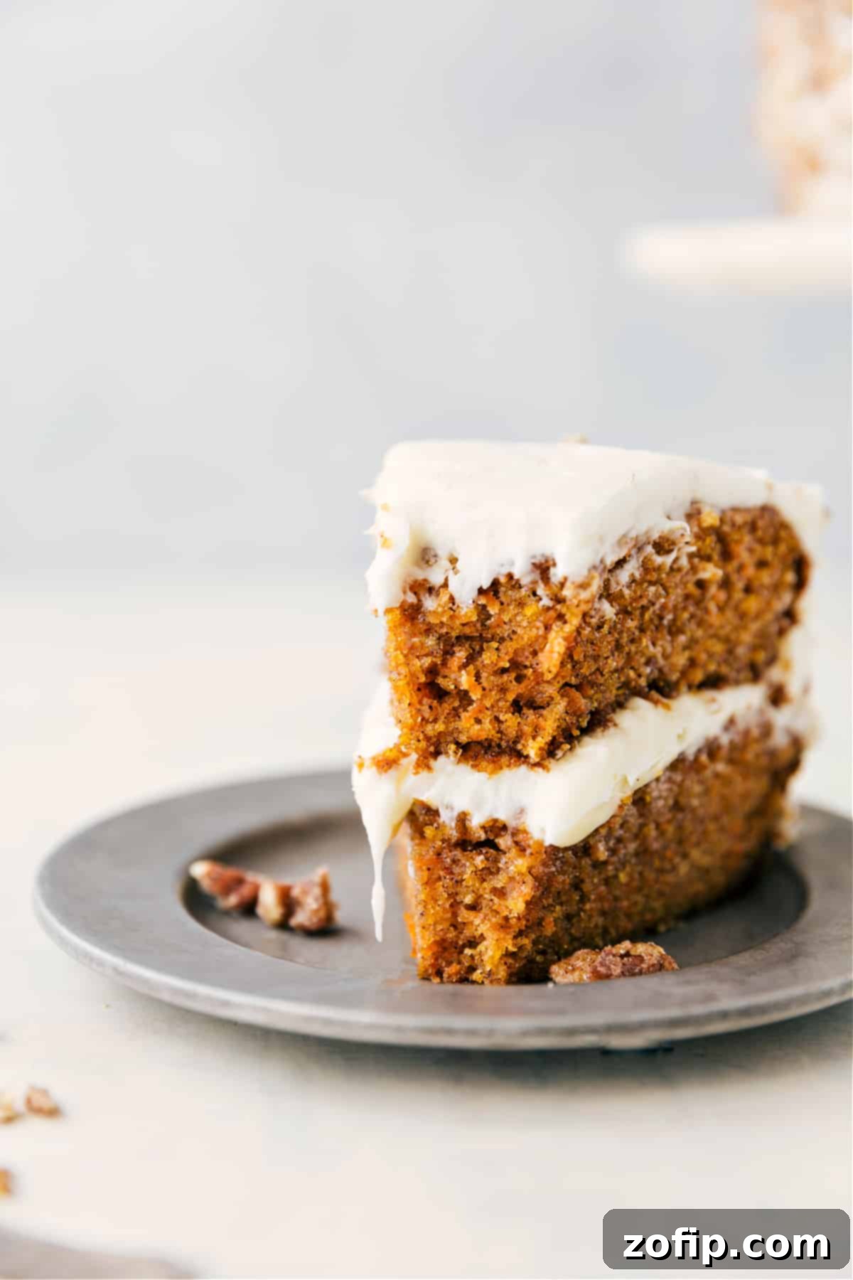 Carrot Cake With The Best Cream Cheese Frosting A delectable slice of moist carrot cake, beautifully layered with tangy cream cheese frosting and visible carrots, with a small bite removed, inviting you to indulge.