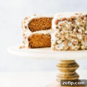 Spiced Carrot Delight 2 A beautifully presented slice of carrot cake, generously frosted and topped with chopped candied pecans, ready to be enjoyed.
