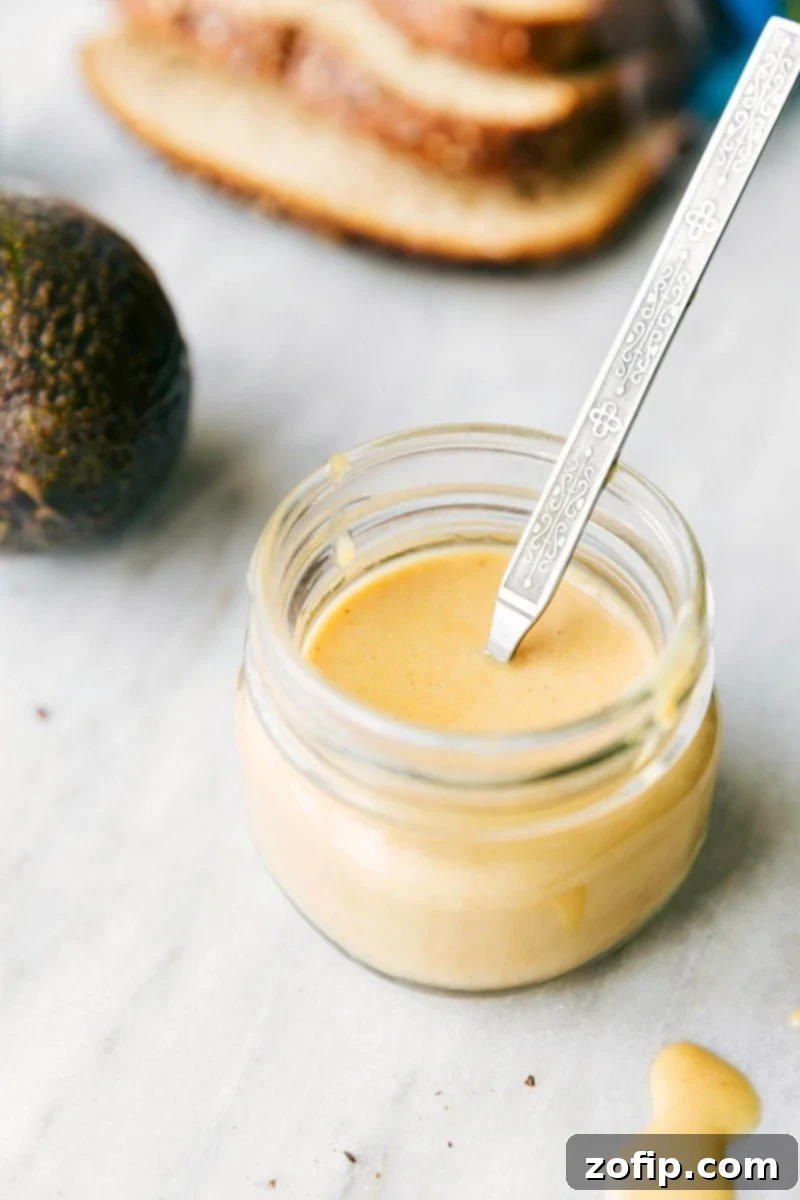 Close-up of a stacked Honey Bacon Club Sandwich, showcasing the layers of perfectly toasted bread, crisp romaine, ripe tomato, creamy avocado, savory turkey and ham, and crispy bacon, all held together with melted Muenster cheese and a generous slather of homemade honey mustard sauce.