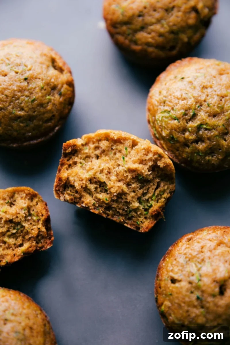 The finished healthy zucchini muffins, one split in half to reveal the moist interior.