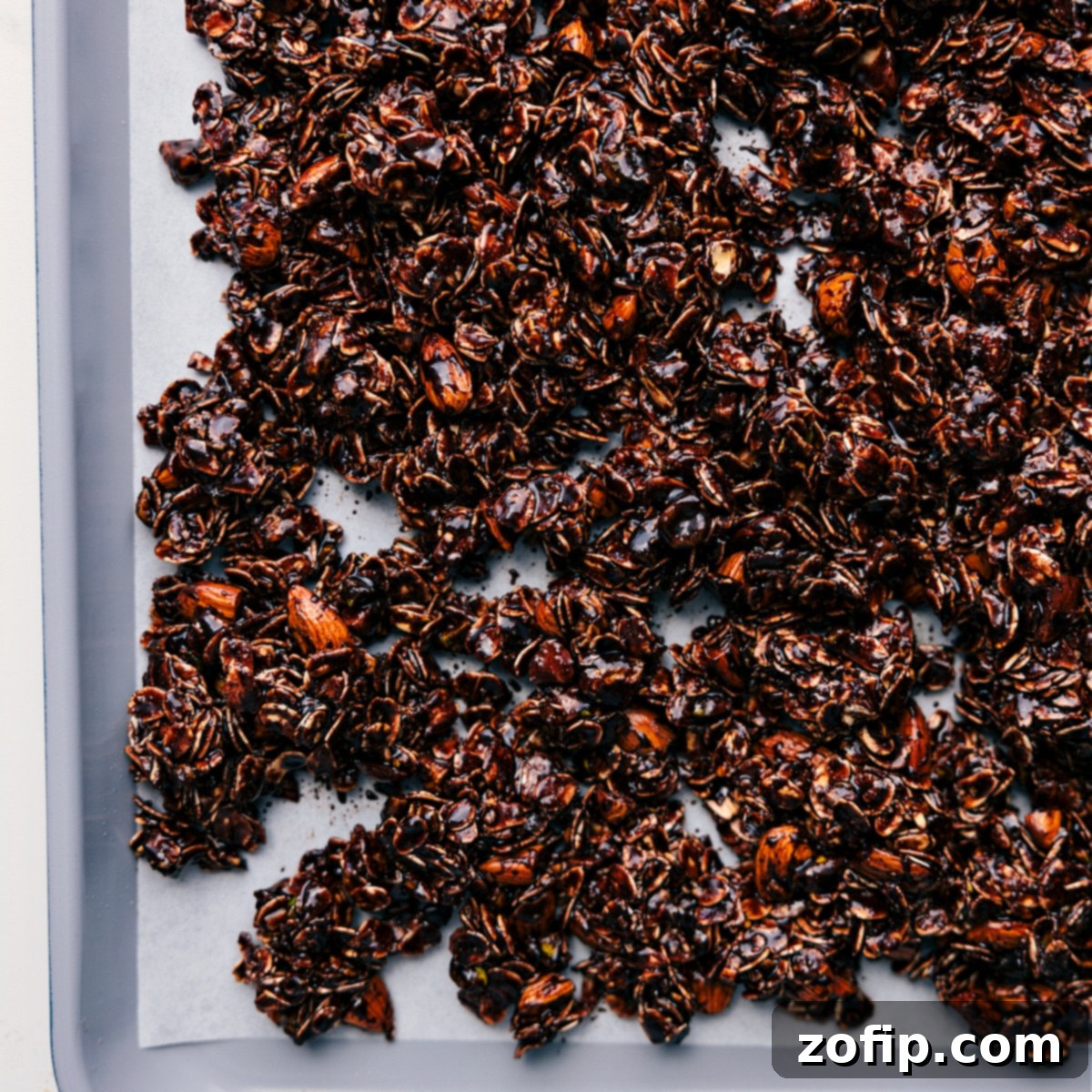 The Perfect Chocolate Granola Recipe The mixed chocolate granola spread evenly onto a large baking sheet, glistening with its rich chocolate coating and perfectly positioned, ready to be baked to crispy perfection in the oven.