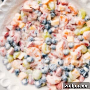 A beautifully presented bowl of creamy fruit salad with yogurt, topped with granola for crunch.