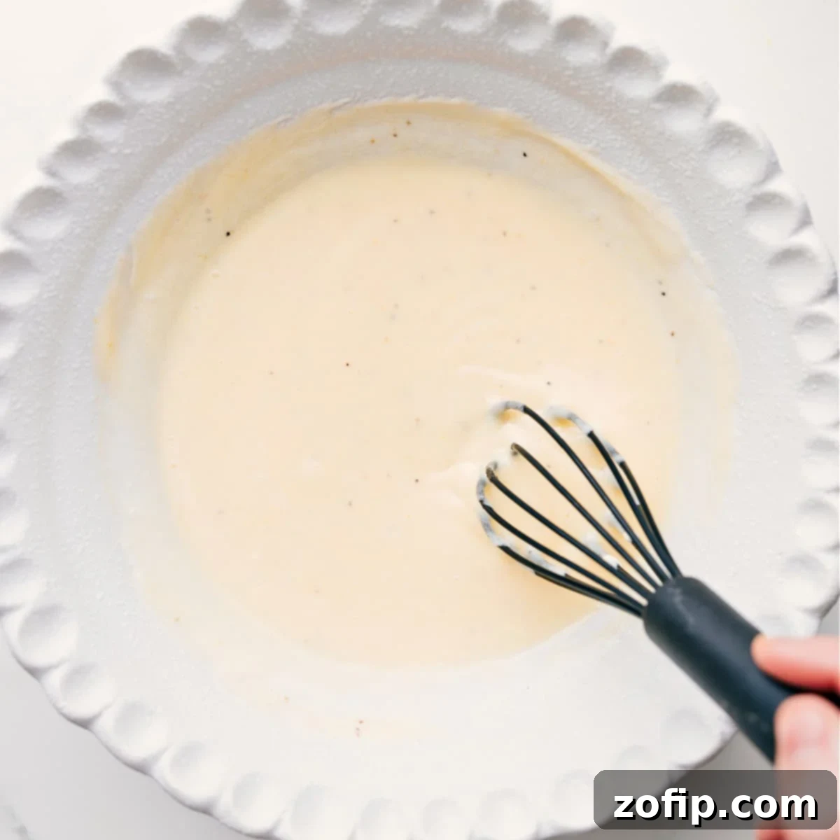 The creamy Chick-Fil-A coleslaw dressing being whisked together in the bottom of a bowl.