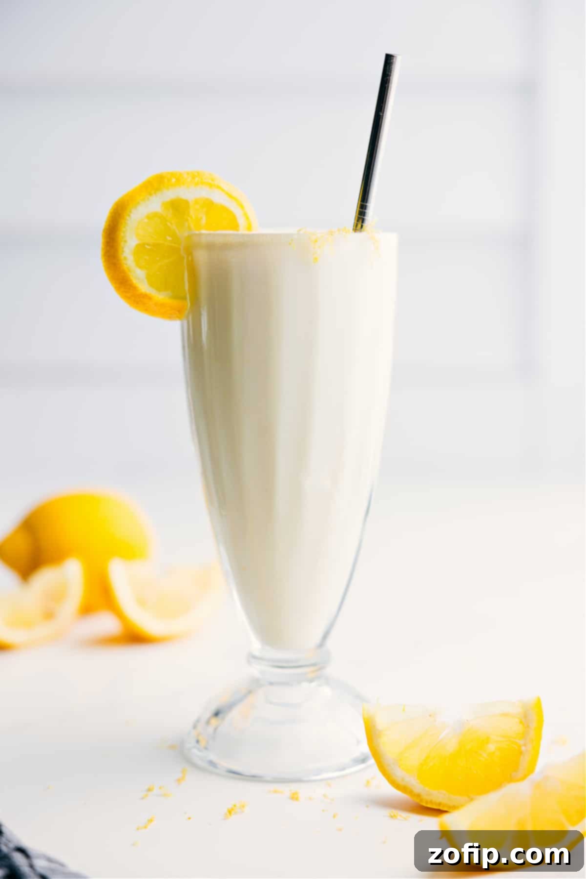 A tall glass of icy, creamy frozen lemonade, garnished with a fresh lemon slice, ready to be enjoyed on a hot summer day.