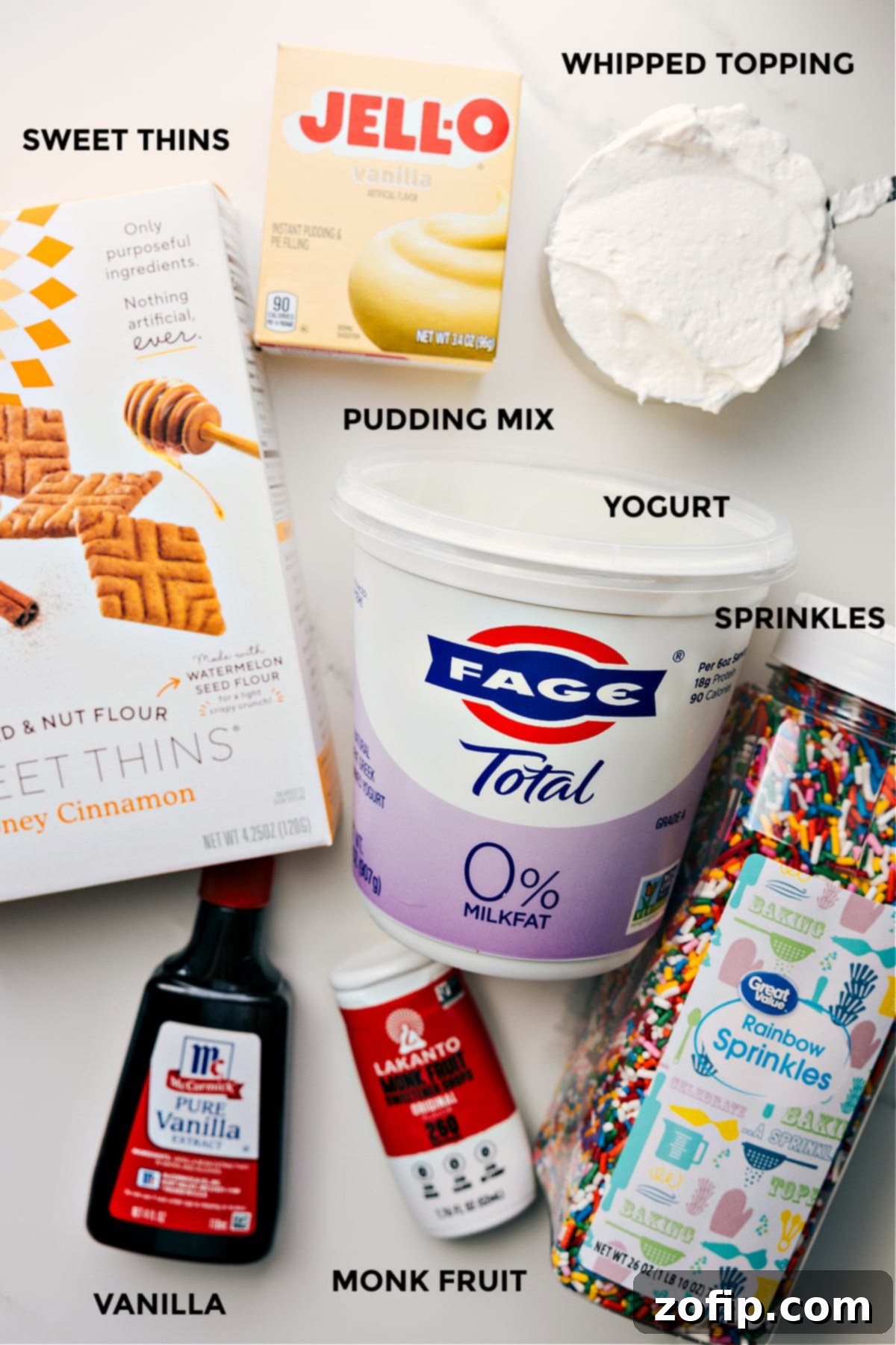 All the ingredients prepped for easy assembly, including graham crackers for dipping, Fage 0% Greek yogurt, colorful sprinkles, liquid monk fruit sweetener, and vanilla extract.