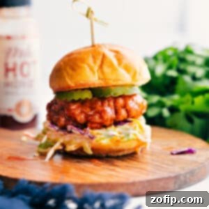 Close-up of a single Hot Honey Chicken Slider, showing the crispy chicken, creamy slaw, and pickles within a toasted brioche bun.