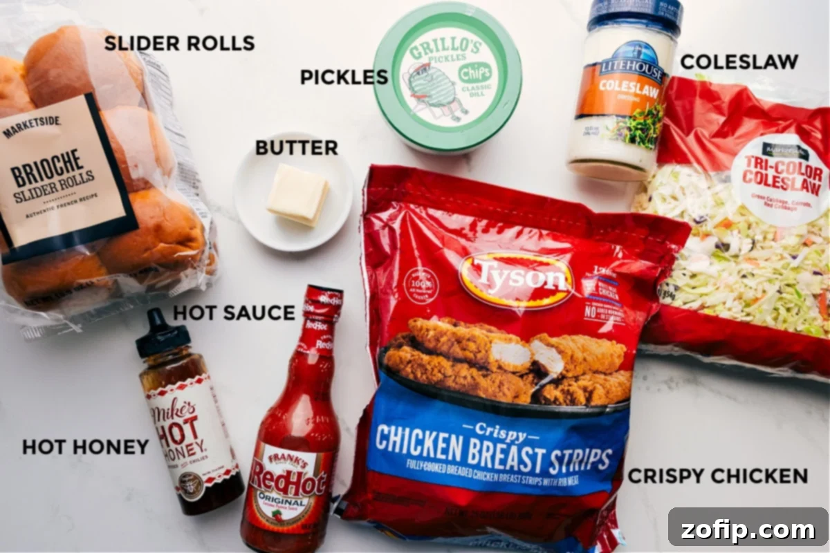 All the essential ingredients for Hot Honey Chicken Sliders laid out: soft brioche buns, golden crispy chicken tenders, fresh coleslaw mix, creamy dressing, a jar of hot honey, a bottle of hot sauce, and tangy pickles.