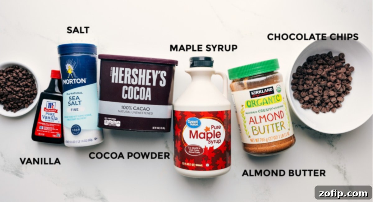 All the key ingredients for Healthy Brownie Batter Bark laid out: chocolate chips, vanilla extract, cocoa powder, maple syrup, and almond butter.