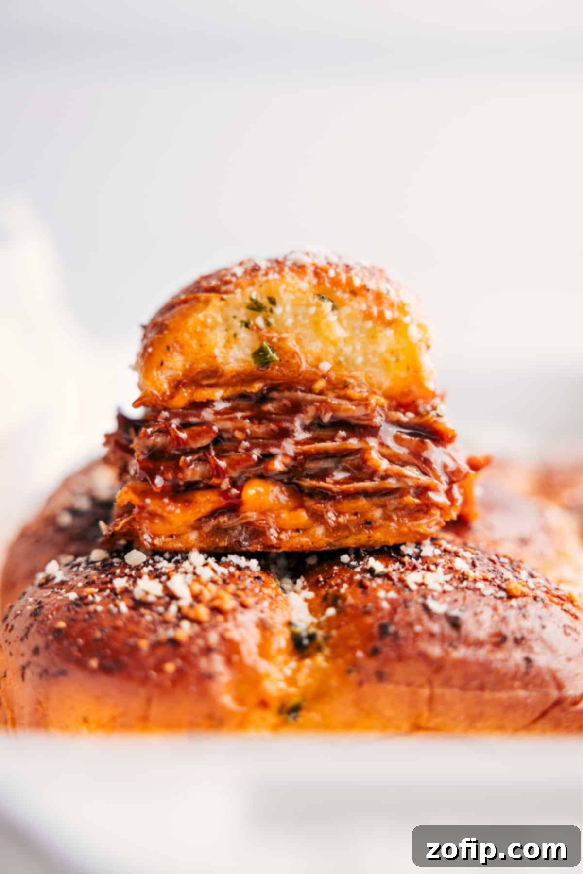 Stacked BBQ Pulled Pork Sliders, golden brown and ready to serve, showing gooey cheese and tender pork filling.