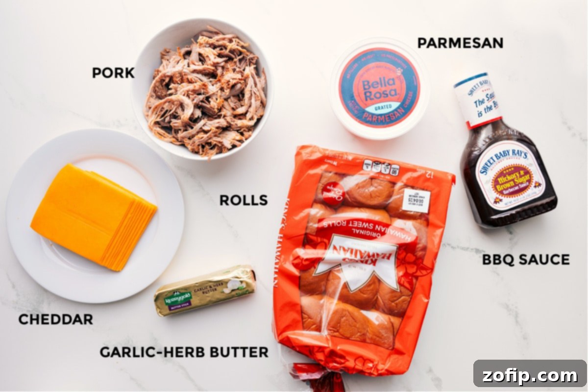All essential ingredients for BBQ Pulled Pork Sliders prepped and arranged: sharp cheddar cheese, garlic-herb butter, King's Hawaiian rolls, shredded BBQ pork, and a bottle of BBQ sauce.