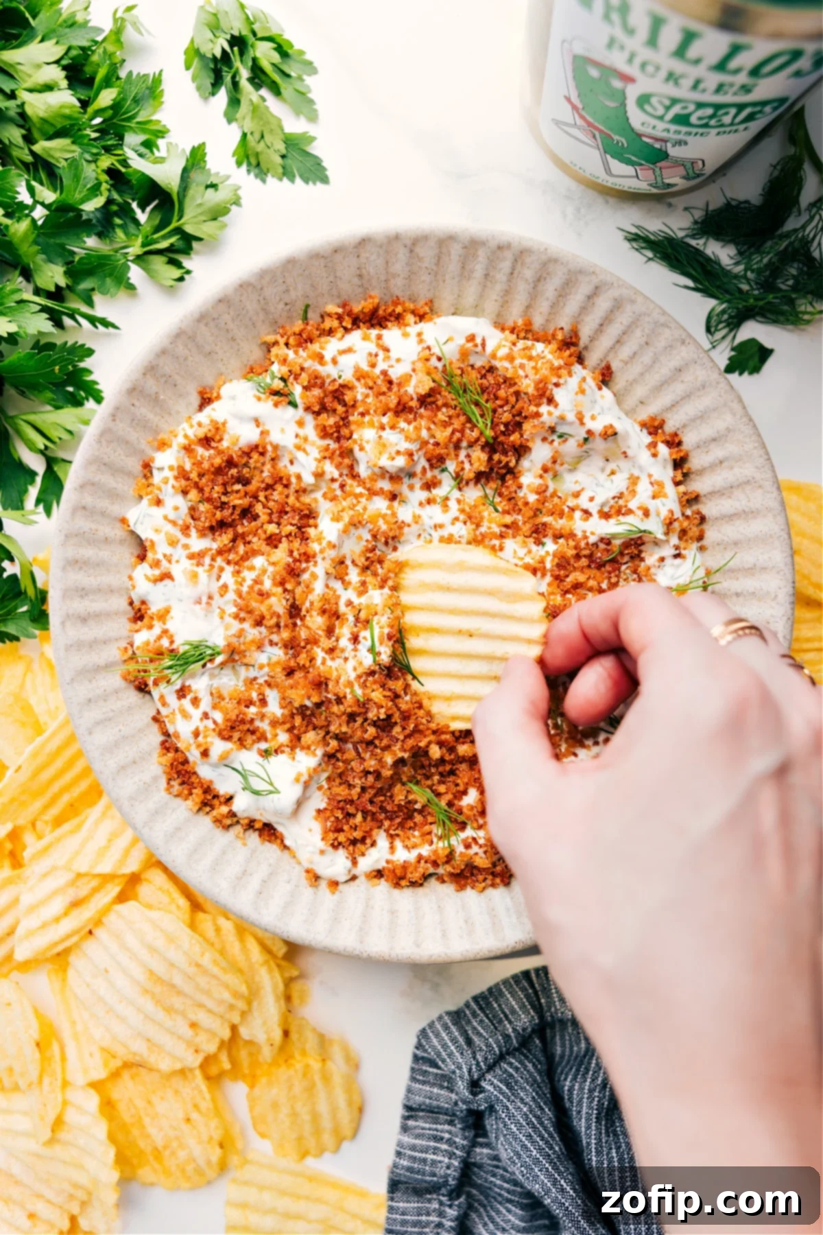 Bowl of Fried Pickle Dip with a chip scooping a bite.