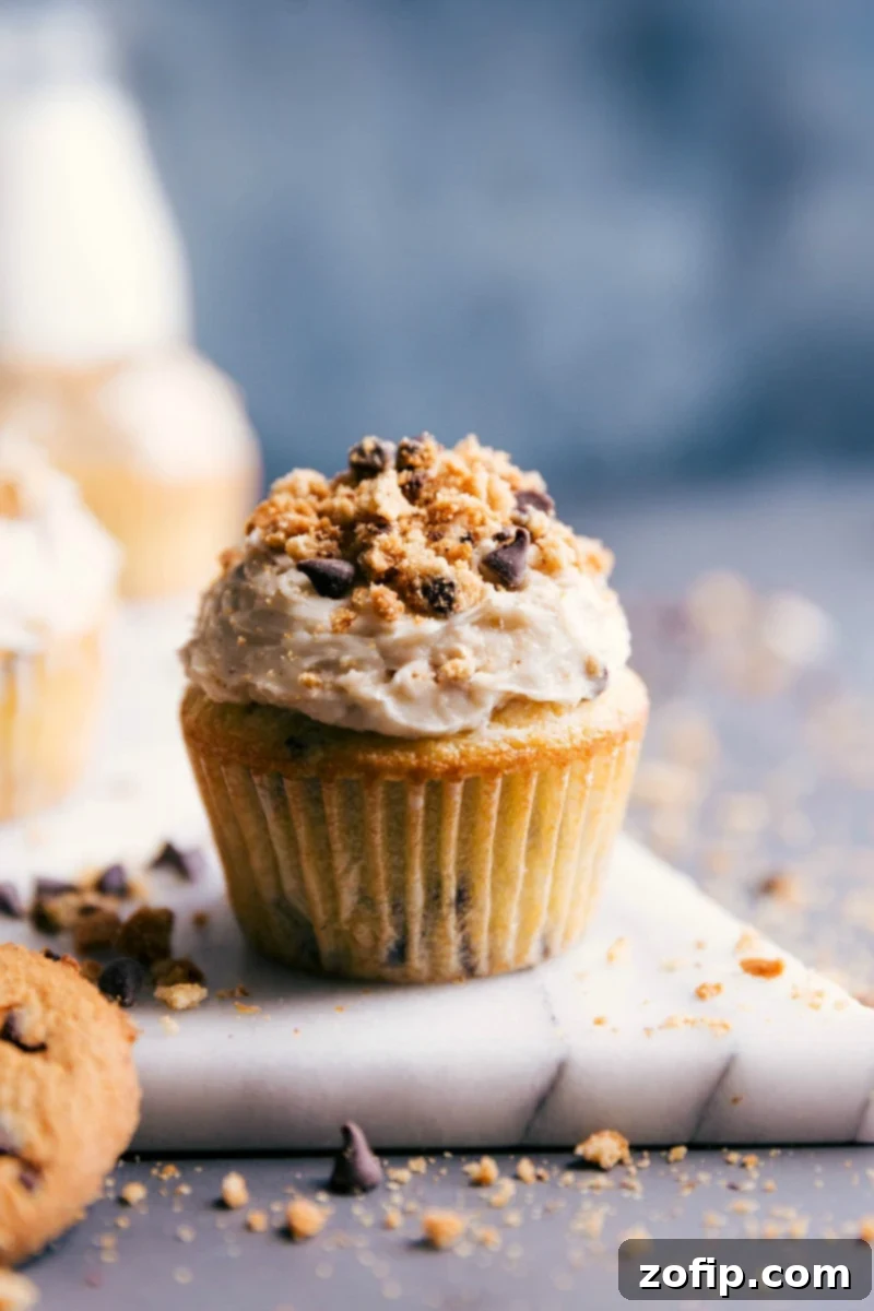 Indulgent chocolate chip cupcakes adorned with luscious cream cheese icing and scattered chocolate shavings, presented beautifully.