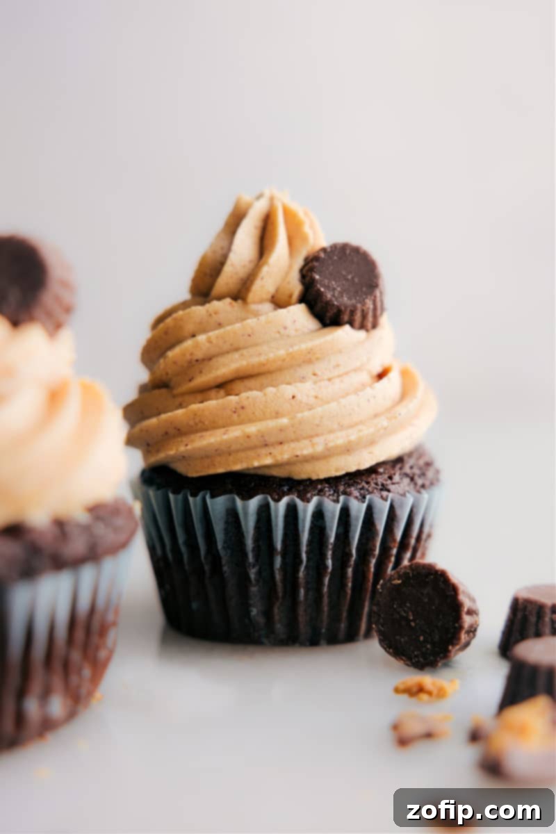 Close-up image of beautifully frosted cupcakes with creamy peanut butter frosting, garnished with chocolate shavings.