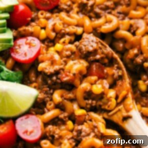 Savory Taco Pasta Delight 3 Spoon scooping up cheesy taco pasta with visible cheese and seasoned meat.