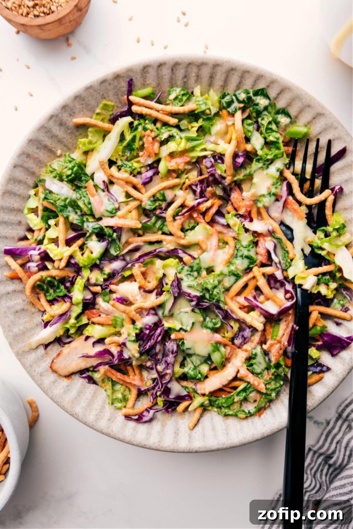 Vibrant Asian Chicken Salad Recipe tossed with an irresistible creamy dressing, ready to be served in a large bowl. Features shredded chicken, colorful cabbage, carrots, and crispy chow mein noodles.