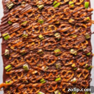 A close-up of Caramel Apple Bark showcasing its layers of chocolate, pretzels, apples, and caramel drizzle, cut into perfect squares.