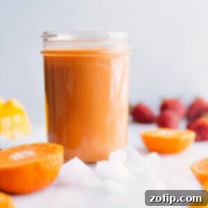 A vibrant and refreshing mango smoothie in a clear glass with a straw, ready to be enjoyed.