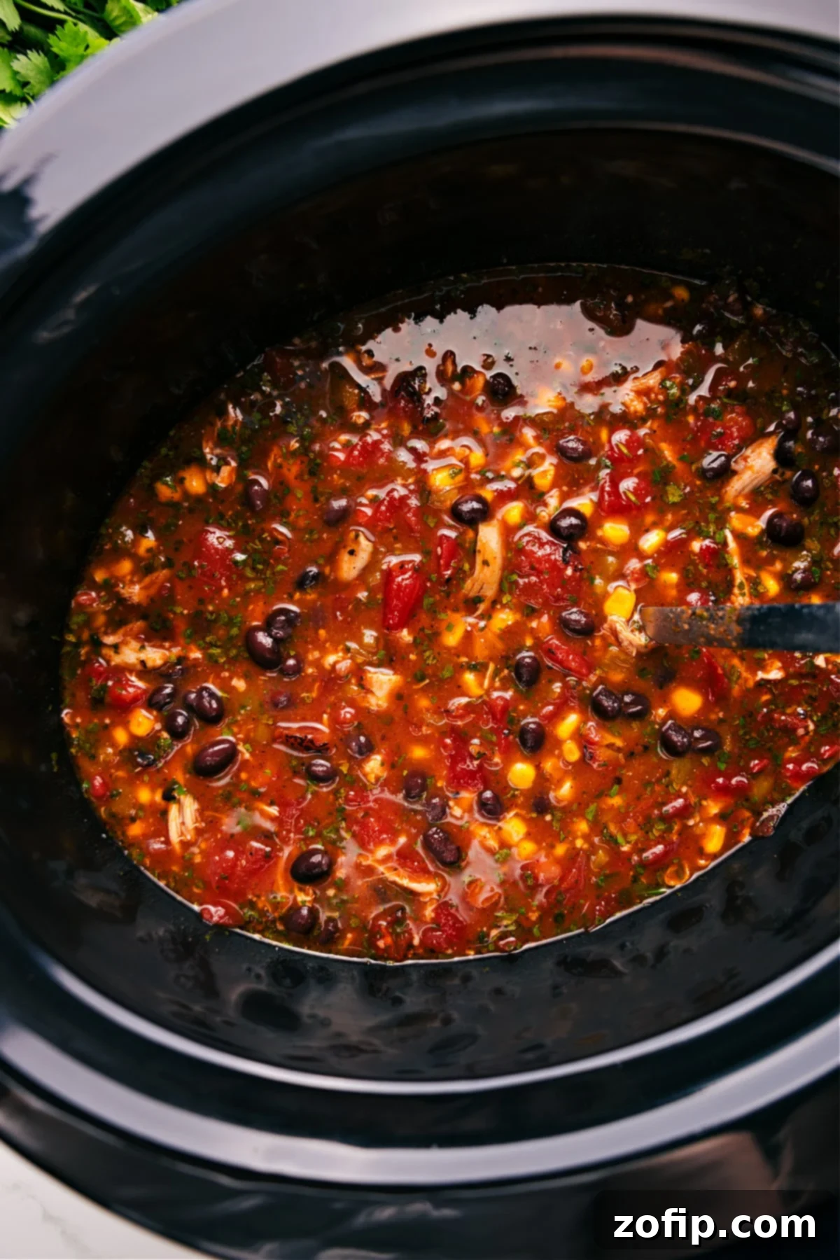 Chicken Taco Soup simmering in the slow cooker, perfectly cooked and ready to be served.