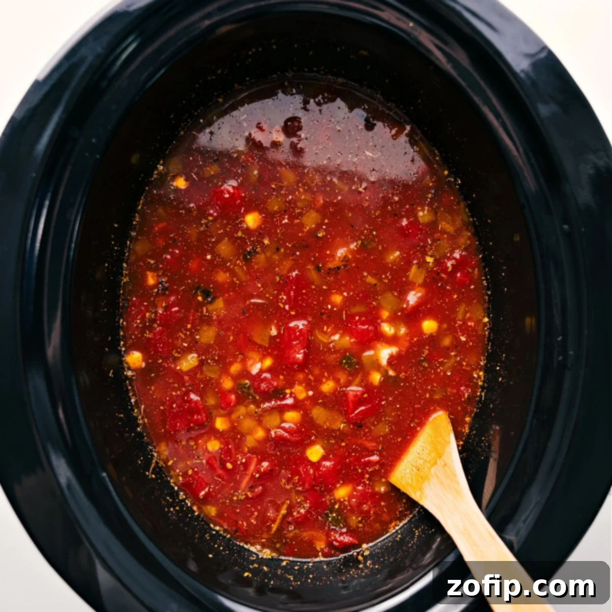 All the prepped ingredients for chicken taco soup have been added to a crockpot, ready to be slow cooked.