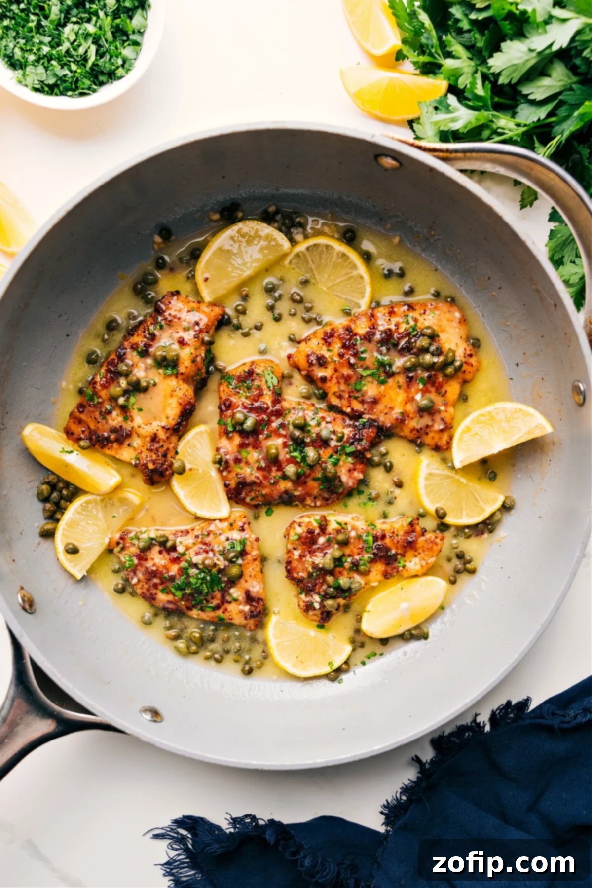 One Skillet Chicken Piccata Recipe: Easy and Delicious Golden-brown Chicken Piccata simmering in a skillet, garnished with fresh lemon slices and parsley, ready to be served.
