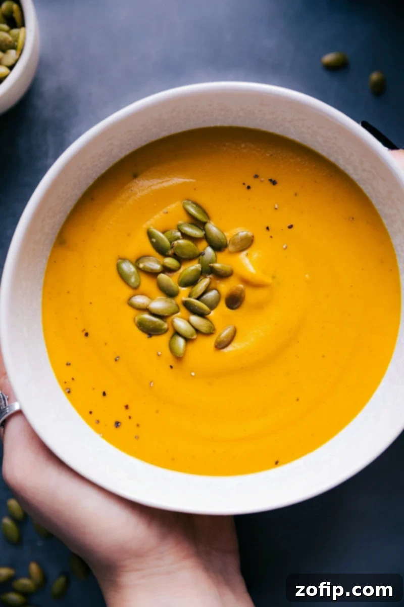 Creamy Sweet Potato Soup Recipe in a rustic bowl, garnished with crunchy pepitas and fresh herbs, ready to be savored.