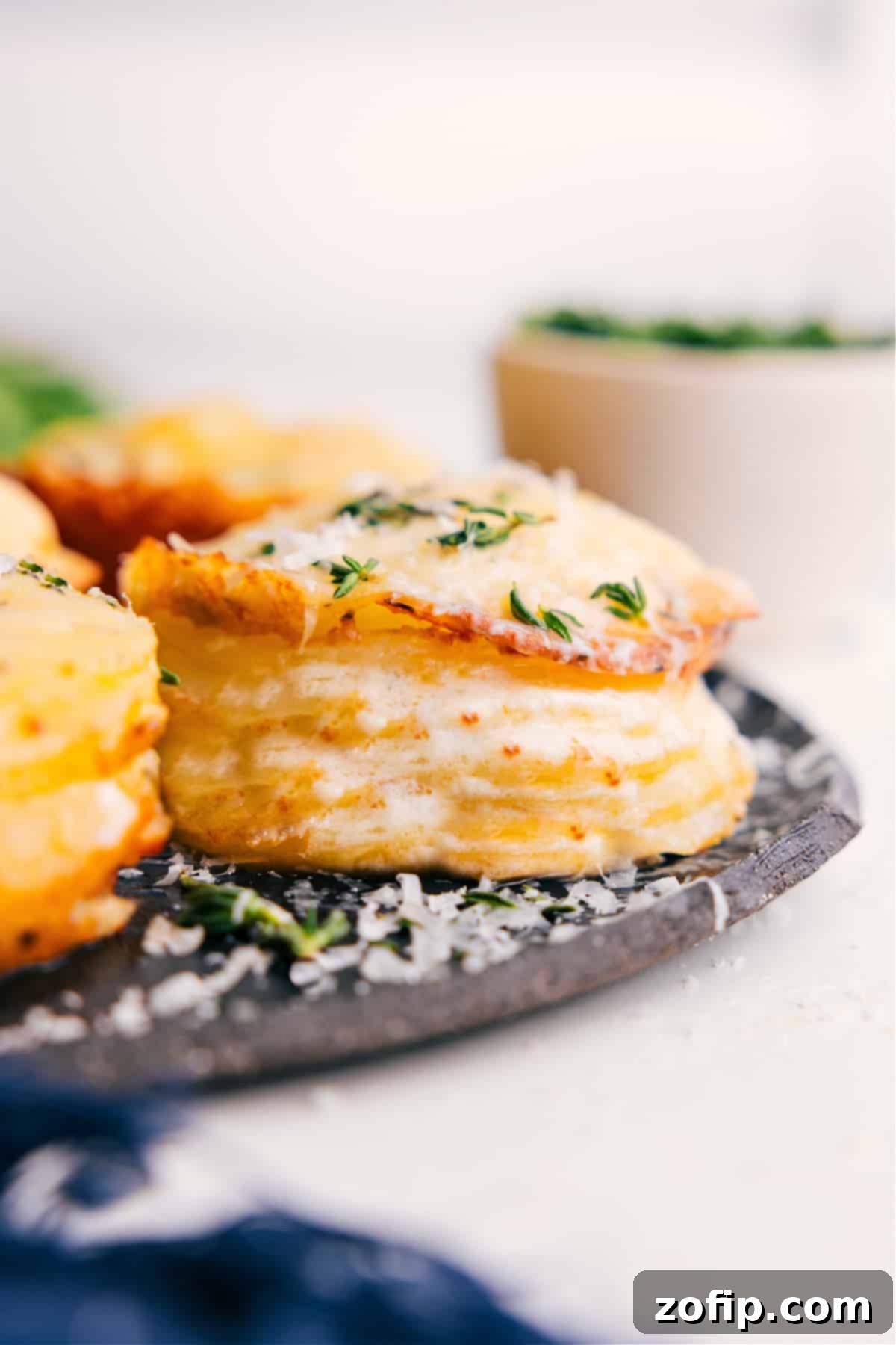 Potato stacks recipe fresh from the oven topped with melted cheese and thyme. Golden brown and bubbly, ready to serve.