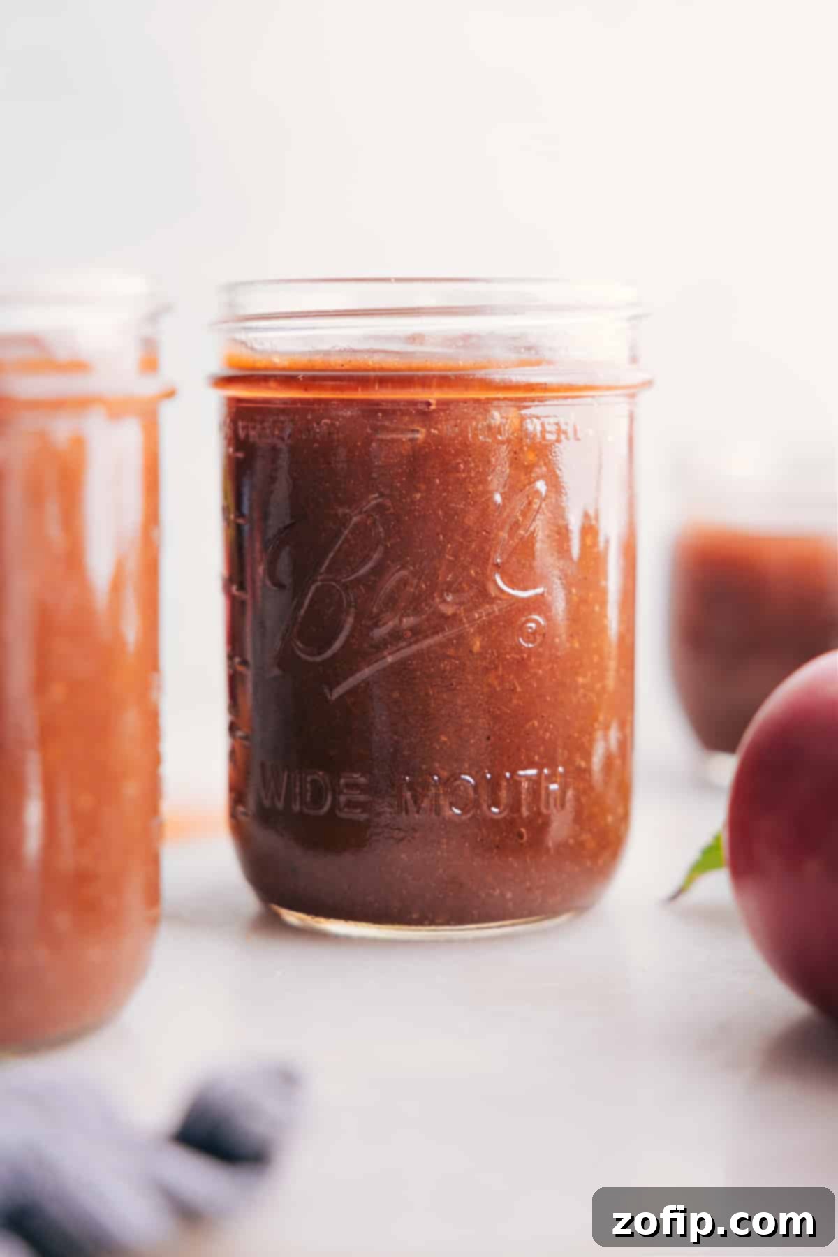 Glass jar filled with rich, smooth Crockpot Apple Butter, showcasing its deep amber color and inviting texture.