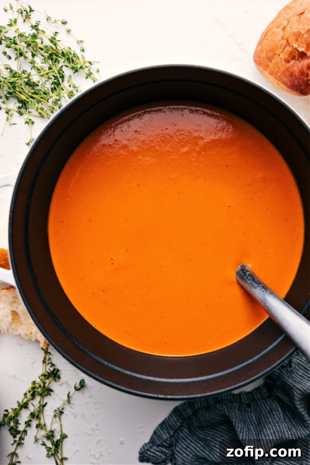 A steaming bowl of creamy Roasted Red Pepper Gouda Soup, garnished with a swirl of cream and fresh herbs, ready to be enjoyed as a comforting meal.