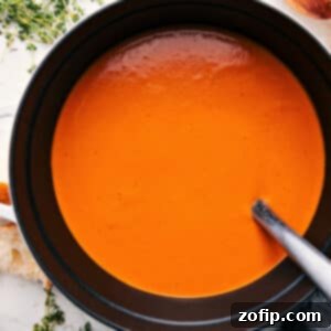 A delicious bowl of Roasted Red Pepper Gouda Soup, garnished with fresh cream and paprika, ready to be served.