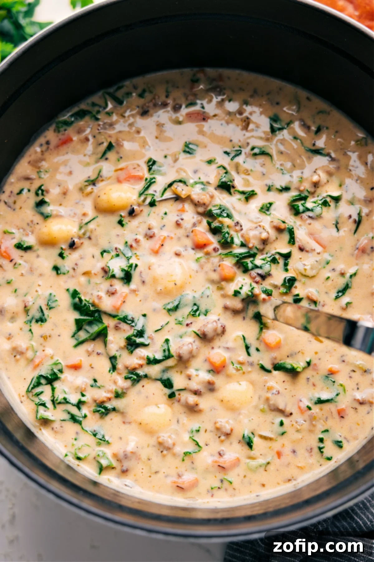 A steaming bowl of creamy Sausage Gnocchi Soup, garnished with fresh thyme leaves, ready to be enjoyed.