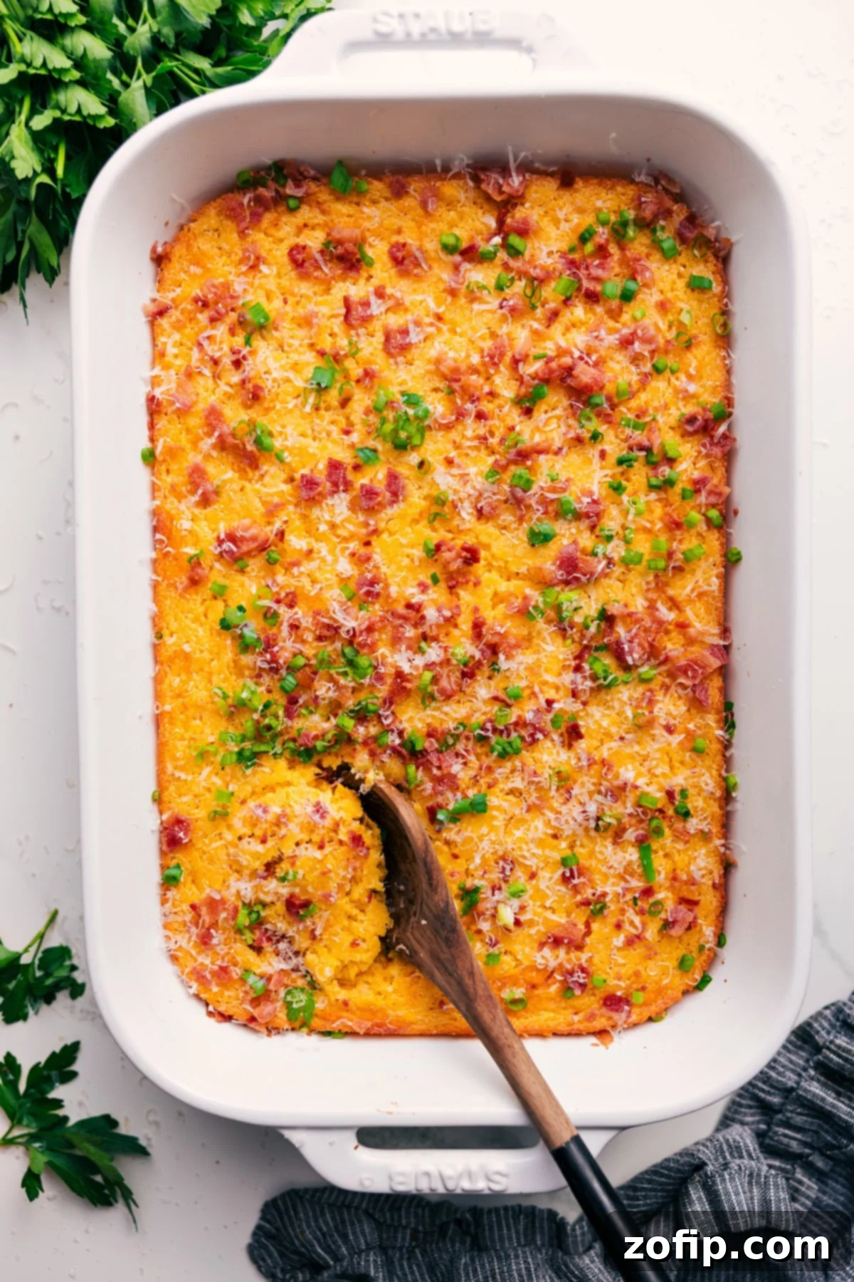 Corn Pudding Casserole in the casserole dish topped with cheese, green onions, and bacon.