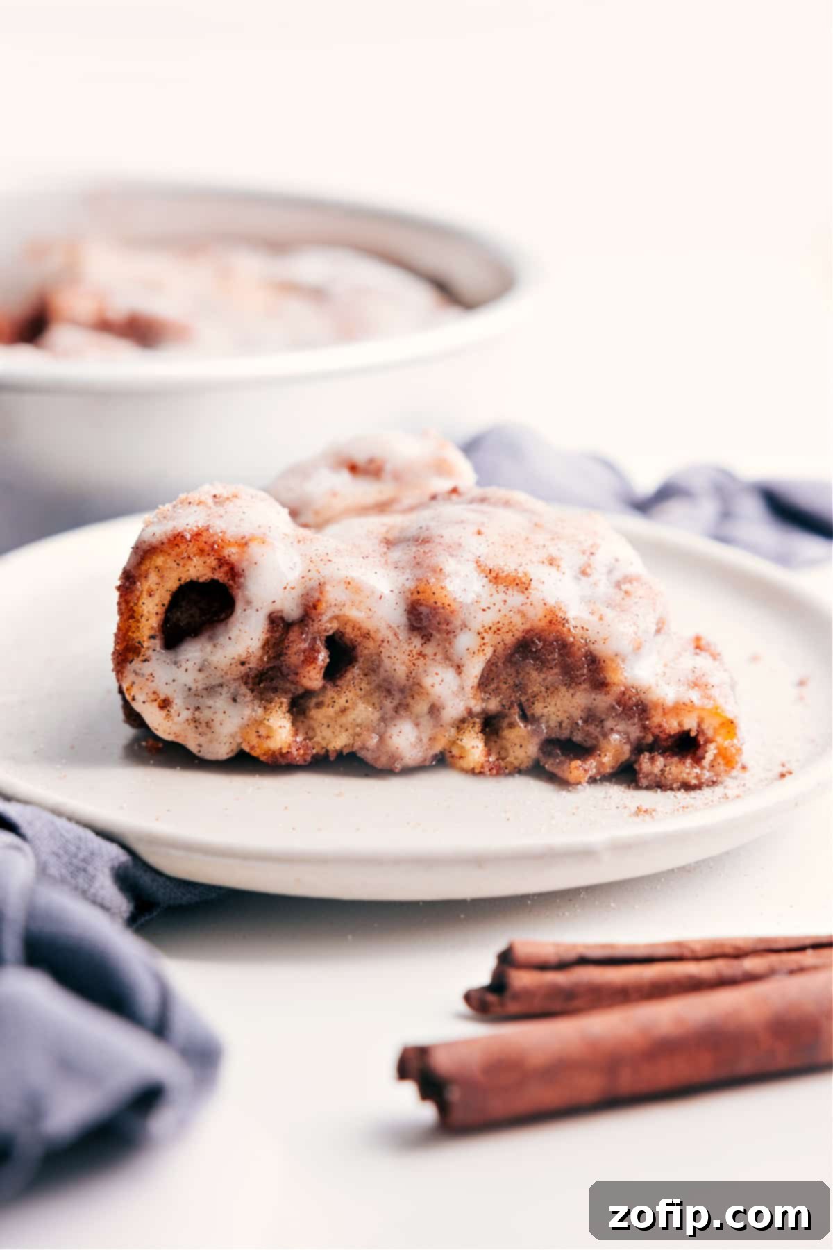 A delectable slice of Cinnamon Roll Cake, featuring a golden crust, visible cinnamon swirls, and generous cream cheese glaze, ready to be savored.