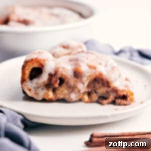 A slice of quick Cinnamon Roll Cake with cream cheese glaze, served on a white plate.