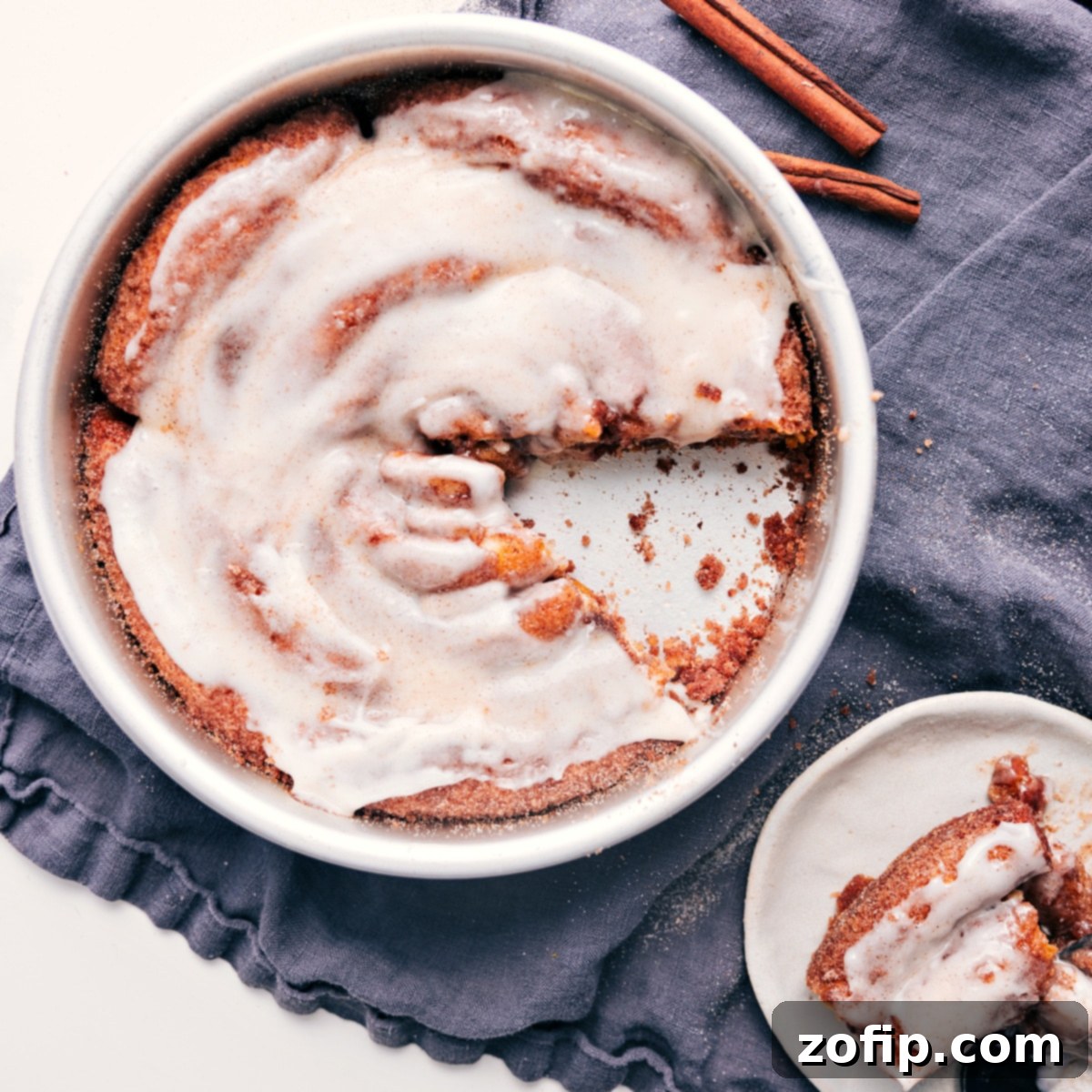 A perfectly portioned slice of Cinnamon Roll Cake, showcasing its delightful spiral layers and generous cream cheese glaze, carefully removed from the pan and ready to be enjoyed.