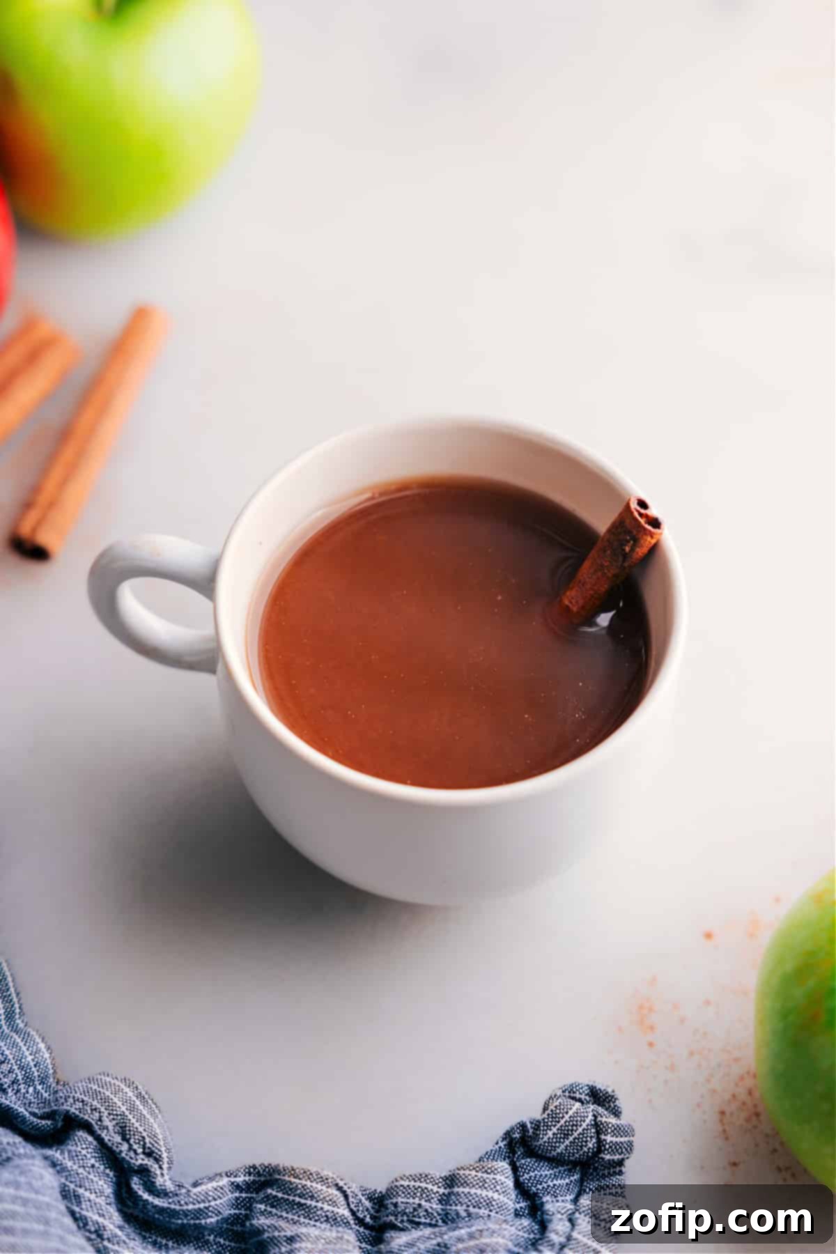 A steaming cup of homemade Hot Apple Cider, garnished with cinnamon sticks and apple slices, radiating warmth and comfort.